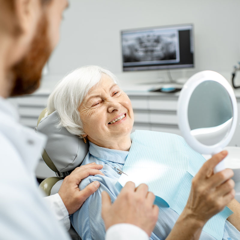 elderly woman looking at her dentures